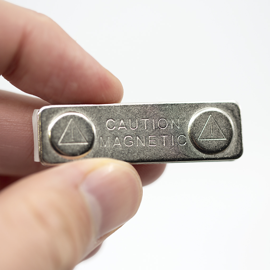 Strong magnetic name badge fastener with caution magnetic warning held in hand