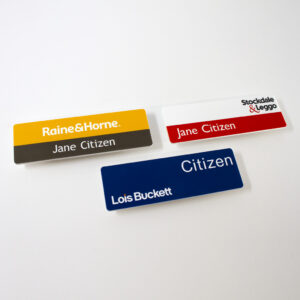 Three magnetic name badges for real estate agencies, featuring designs for Raine & Horne, Stockdale & Leggo, and a blue badge for Lois Buckett.