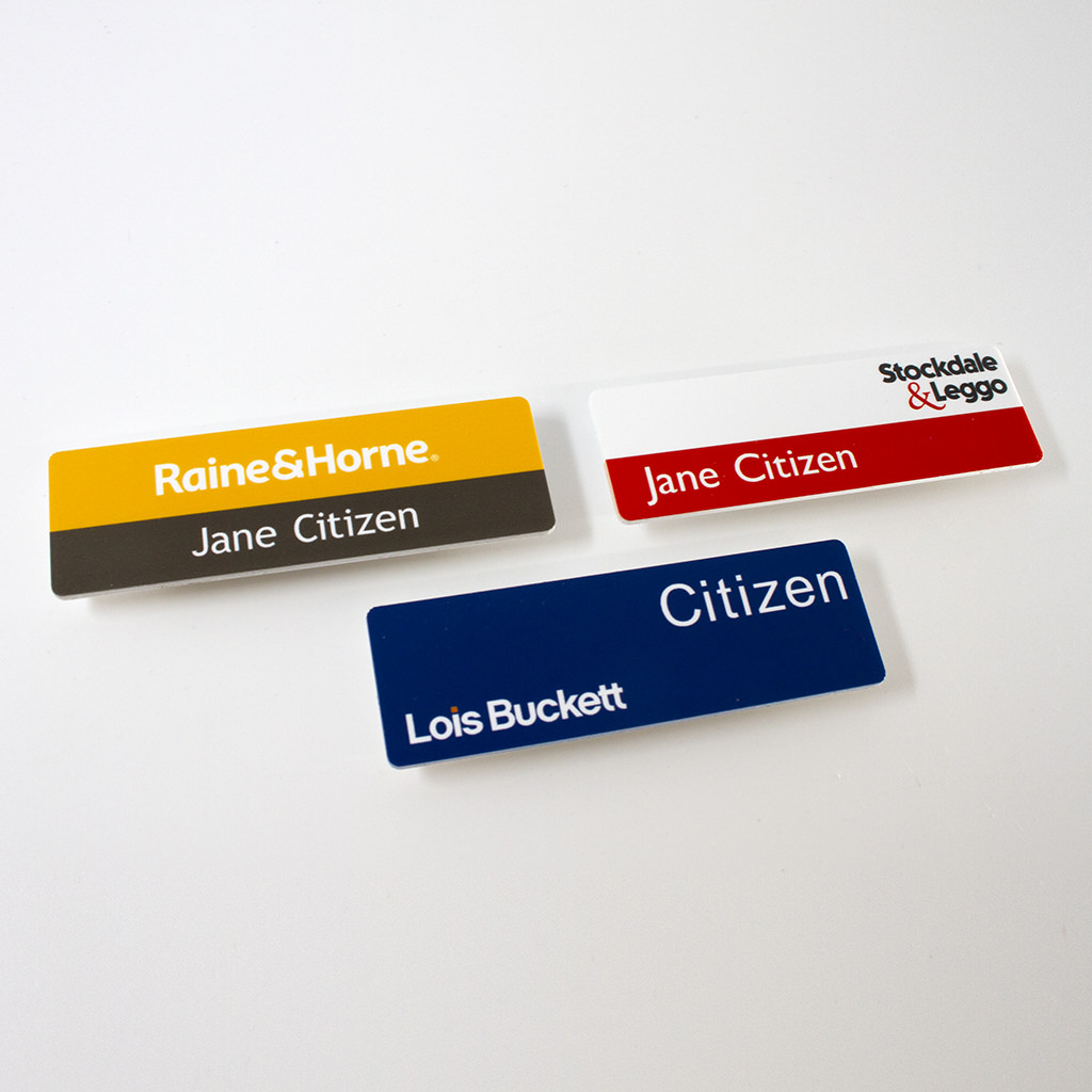 Three magnetic name badges for real estate agencies, featuring designs for Raine & Horne, Stockdale & Leggo, and a blue badge for Lois Buckett.