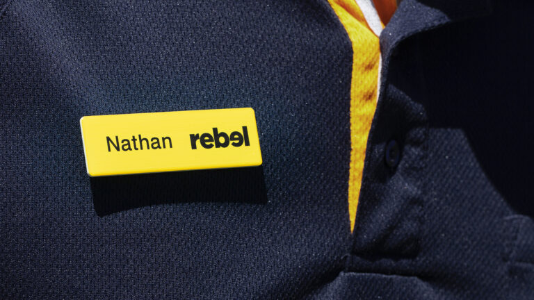 Yellow name badge reading Nathan on a Rebel staff uniform