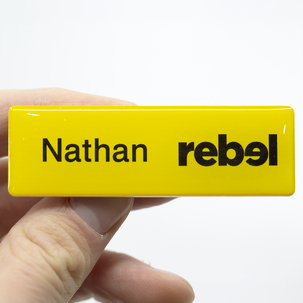 Yellow magnetic name badge featuring the name Nathan and the Rebel brand logo.